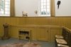 Interieur, binnen de dooptuin: kerkenraadbank aan rechterzijde van de preekstoel met opschrift kerkeraad.Links op de voorgrond een standaard voor collectezakken en uiterst links een houten doopvont met deksel.