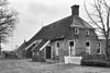 Kleine boerderij met woondeel tegen afgeknotte topgevel onder wolfsdak en met schuurdeel met zijbaander