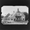 Reproductie van en oude foto: overzicht boerderij met uitbouw en poserende mensen, opname van circa 1900