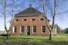 Overzicht van de voorgevel van het woongedeelte met zicht op de serre aan de rechter zijgevel