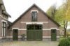 Koetshuis, aanzicht voorgevel waarin een getoogde schuurdeur, snijwerk en oorspronkelijke roedeverdeling.