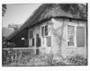 Woongedeelte van rietgedekte boerderij, met kruisvensters, schuifvenster en luiken.