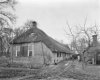 Voorgevel en zijgevel van rietgedekte boerderij, twee schuiframen met roedenverdeling en luiken in de voorgevel, erf