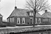 Landelijk pand met goot op klossen onder schilddak met hoekschoorstenen (vormt een geheel met nr. 26)