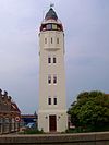 Harlingen vuurtoren -  Harlingen - Feuerturm Frysk: Harns - Fjoertoer  Harlingen: Vuurtoren. Uit 1921 daterende, vierkante vuurtoren (hoge licht) uit baksteen en beton opgetrokken naar ontwerp van C.Jelsma. De toren is 16,31 m. hoog, is bepleisterd en grijs en wit geschilderd en heeft 5 etages. De toren springt boven de begane grond iets in en de muurvlakken van de bovenste verdieping kragen tussen de rechte hoeken driezijdig uit. Rechtgesloten toegangsdeur en rechtgesloten, hoge en smalle vensters. Lichthuis met ko…