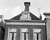 Pand met gesneden kroonlijst onder zadeldak met voorschild met dakkapel en topschoorsteen met bord