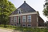 Boerderij met ingebouwd onderkelderd dwars woonhuis met hoge toegangstrap, omgaande geblokte kroonlijst en dakkapel boven de ingang