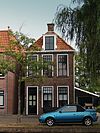 Diep pand met volledige verdieping onder zadeldak met voor- en achterschild en hoge zesruitsvensters in voor- en zijgevel