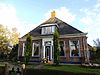 Kop-rompboerderij met zesruitsvensters en topgevel met diagonaal gemetselde lijsten met houten boeiborden en schoorsteen met pyramidevormig bord