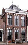 Pand met verdieping onder vrij laag en diep voor afgeschuind zadeldak met gevel met neo-empire-snijwerk op de kroonlijst