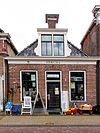Laag pandje onder zadeldak met topschoorsteen met bord boven voorste dakschild