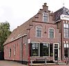 Diep pand met verdieping en zolderverdieping, onder zadeldak tegen geheel bakstenen trapgevel met toppilaster