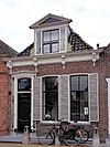 Woonhuis met omlijste ingang en gootlijst met vier gebeeldhouwde consoles onder voor afgeschuind zadeldak met grote dakkapel