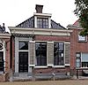 Woonhuis met omlijste ingang en kroonlijst met consoles onder voor afgeschuind zadeldak