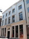 Huis met lijstgevel met middenrisaliet, geheel met natuursteen bekleed. Rijk geprofileerde kroonlijst. Achterkamer met stucplafond, Lod. XV