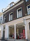 Huis met gevel met boven de kroonlijst in het hoge zadeldak een dakvenster met fronton en gebosseerde vleugelstukken. Inwendig gesneden trapleuning, Lod. XV