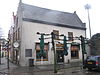 Hoekpand met gewijzigde trapgevel en aan de achterzijde gepleisterde puntgevel met tweelichtskozijnen en zaagtandfries