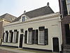 Dwarshuis van alleen begane-grond met hoog, dwars schilddak, waarop hoekschoorstenen