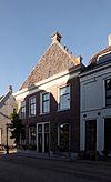 In kern mogelijk 16e-eeuws huis met hoog schilddak. Lijstgevels. Begane grond met een verdieping. Schoorstenen op het schilddak