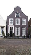 Huis met klokgevel met rococoversieringen rond het topvenster