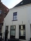 Woonhuis achter een gepleisterde en afgeschuinde lijstgevel met nr 16 met schuiframen