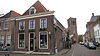 Hoekpand van Kinsbergenstraat met moderne gevels onder lijsten en hoog schilddak, waarin dakvenster met hijsnok. Stoep met palen