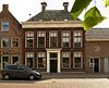 Gaaf bewaard, deftig herenhuis met verdieping en dwars schilddak, waarop hoekschoorstenen met kappen