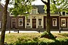 Dwarshuis van begane-grond met zadeldak tussen puntgevels, die topschoorstenen met kappen dragen