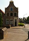 Pand met gaaf bewaarde, bakstenen topgevel met ingezwenkte zijkanten, gebeeldhouwd fronton met schelpversiering en natuurstenen hoekvoluten