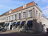 Gepleisterd pand ter breedte van vijf vensterassen met verdieping en zadeldak en gepleisterd hoekpand ter breedte van acht vensterassen met verdieping en een mansardekap