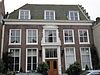 Nieuwstraat 10 - Herenhuis uit de 17e eeuw met verdieping en hoog zadeldak. Aan de voorzijde een lijstgevel met in Lodewijk XV-stijl uitgevoerde omlijsting van het venster boven de deur, dat bekroond wordt door een gebogen fronton. De deur wordt geflankeerd door verdiepte pilasters, die een hoofdgestel dragen. In de vensters zes- en vierruitsschuiframen. Smeedijzeren lantaarns te weerszijden van de deur. 