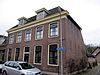 Gepleisterde stadsboerderij onder pannen zadeldak tussen puntgevels