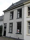 Kerkplein 26 - Gepleisterd pand met verdieping en zadeldak, waarschijnlijk 17e eeuw. Voorgevel met vensters en kroonlijst van 19e eeuws karakter 
