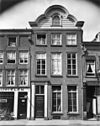 Pand met gevel met boven de kroonlijst een zware, in hout uitgevoerde, gelobde top, waarin dakvenster met segmentvormige afsluiting