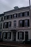 Statig herenhuis met schilddak en gepleisterde lijstgevel met stucwerk en balcon