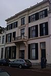 Statig herenhuis met schilddak en gepleisterde lijstgevel met stucwerk en balcon