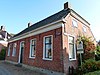 Eenvoudig pand onder zadeldak met wolfeinden waarop hoekschoorstenen
