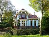 Spijk - Hoofdweg-Noord 27 (2) -  Rentenierswoning in Overgangsstijl met Art Nouveau-elementen met aangebouwd koetshuis aan de Hoofdweg-Noord 27 in het Groningse dorp Spijk.