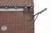Detail van rechterdeel voorgevel, gevelbeÃ«indiging bovenkant met uitkragend metselwerk en gootklossen, buitenlantaarn en gevelsteen