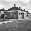 Woning onder laag schilddak met hoekschoorstenen en met ingang in risaliet