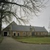 Overzicht van de voorgevel van het poortgebouw, rechterdeel is woonhuis en links zicht op een deel van de schuur