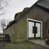 Overzicht van de toegang van de schuur, links van de dubbele deur een gevelsteen.