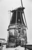Korenmolen in vervallen staat in sneeuwlandschap, van opzij gefotografeerd