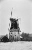 Korenmolen in vervallen staat in sneeuwlandschap, van opzij gefotografeerd