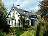 Zuidhorn - De Gast 11 -  Villa 'Geertruida' aan De Gast 11 in Zuidhorn. Gebouwd in 1908 in opdracht van de Zuidhorner burgemeester Dirk Marten Kruisinga. Opgetrokken in eclectische stijl met Chaletstijlelementen. De aangebouwde serre (rechts) dateert van 1910. In 1978 werd de villa verbouwd. Het pand is deels omgracht.