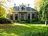 Zuidhorn - De Gast 2 -  Rentenierswoning (dwarshuis) met aangebouwd koetshuis en achterhuis (met serre) aan De Gast 2 in Zuidhorn. Gebouwd rond 1885 in eclectische stijl. Verbouwd in 1946 (door A. Siekman) en 1963. Omgeven door grote voor- en achtertuin. In de voortuin staan monumentale bomen.