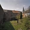 Zicht op gevels Pandhof vanuit het zuidoosten, rechts de oude parochiekerk - Brunssum - 20344038 - RCE -  Voormalige Abdij Sint Benedictus En Sint Clemenskerk: Zicht op gevels Pandhof vanuit het zuidoosten, rechts de oude parochiekerk 