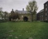  Overzicht van de buitenzijde van een vleugel van het complex met dakkapellen en een torentje met klok en met aan weerszijden een hoektoren