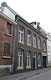 Huis, met in de vernieuwde voorgevel segmentboogvensters in hardsteen, en een koetspoort in hardstenen omlijsting.
