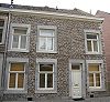 Huis met eenvoudige lijstgevel, voorzien van hoekblokken en een ingang en vensters in Naamse steen.